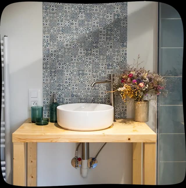 Chambre 1 - Evier sur un meuble en bois de 70cm avec un pot de fleurs séchées au fond à droite du meuble