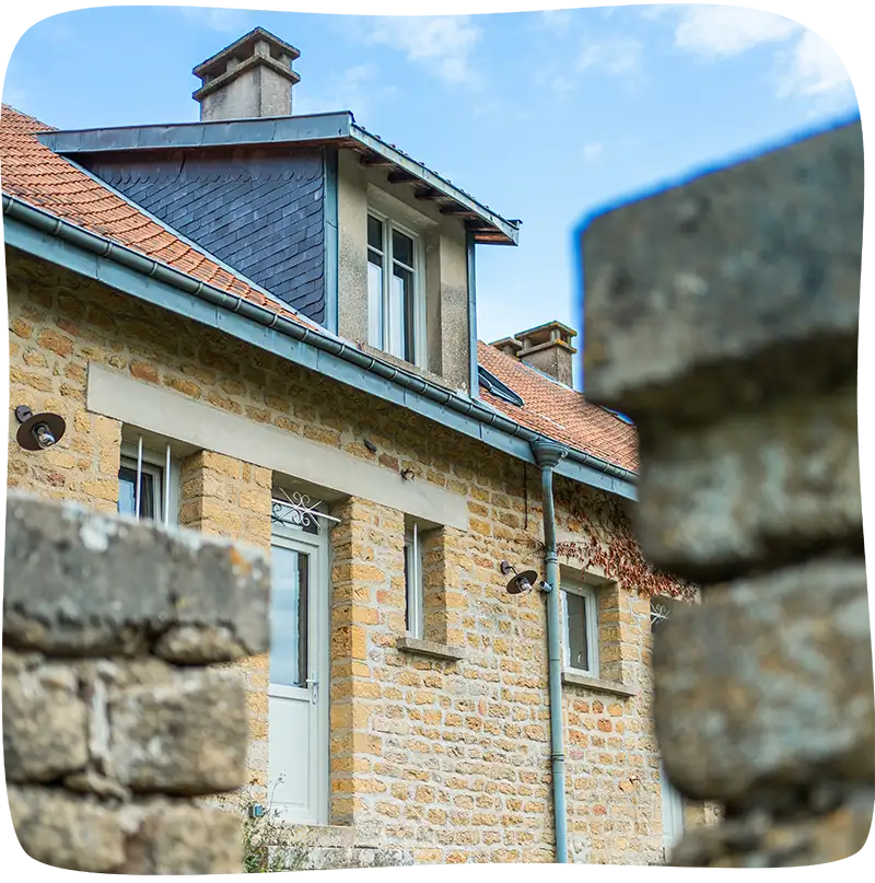 Façade avant de la maison prise entre deux poteau de pierre flous en avant plan